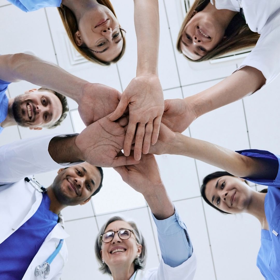 healthcare professionals joining hands in a circle